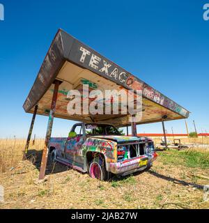 Abgebrochener Pickup-Truck an einer stillgelegten Texaco „The Texas Company“-Tankstelle oder einem Vordach in Texas, USA Stockfoto