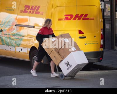 Dynamic Parcel Distribution, DPDgroup, uniformierte DPD-Fahrerin mit Paketzustellung in London, die am rivalisierenden DHL-Van vorbeiläuft Stockfoto