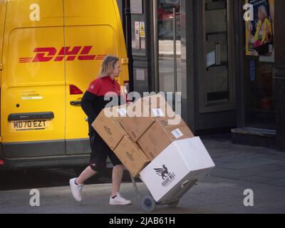 Dynamic Parcel Distribution, DPDgroup, uniformierte DPD-Fahrerin mit Paketzustellung in London, die am rivalisierenden DHL-Van vorbeiläuft Stockfoto