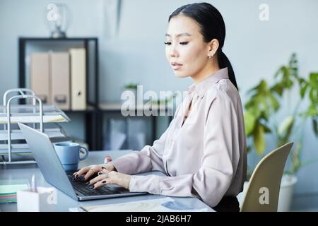 Porträt einer eleganten asiatischen Frau, die einen Laptop benutzt, während sie das Unternehmen leitet und im Büro an Projekten arbeitet Stockfoto