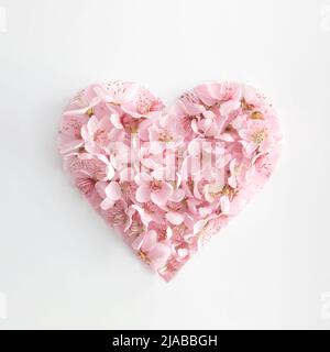 Herzform aus rosa natürlichen Frühlingsblumen. Liebe oder Muttertag Minimal Konzept. Valentinstag oder 8 März Idee. Flach liegend. Speicherplatz kopieren. Stockfoto