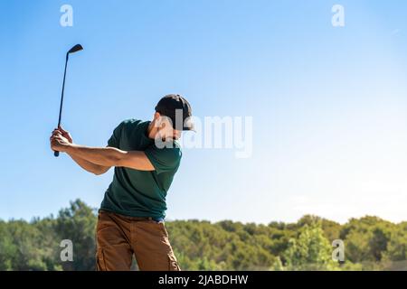 Junger Mann, der im Sommer Golf spielt. Lifestyle-Spiel. Gesund und sportlich im Freien. Konzept der Konzentrationsfähigkeit. Stockfoto