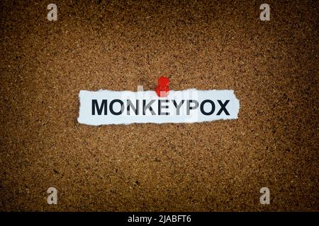 Ein Stück Papier mit dem Wort monkeypox darauf an einem Korkbrett fixiert. Nahaufnahme. Stockfoto