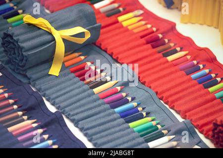 Viele bunte Bleistifte in einer Reihe. Organisieren Sie die Sammlung von Zeichenstiften in einem Textilhalter. Stockfoto