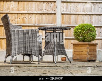 Graue Rattan-Gartenstühle und Tisch auf einer Terrasse Stockfoto