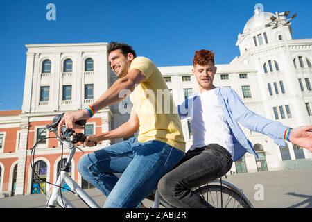 Junge schwule Pärchen genießen eine Fahrradtour zusammen im Freien. LGBT, Beziehungs- und Gleichstellungskonzept. Stockfoto