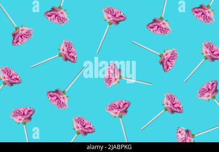 Muster aus pastellrosa Rosen mit Lollipop-Stäbchen. Minimaler Sommergedanke. Kreatives Süßigkeitenkonzept. Stockfoto