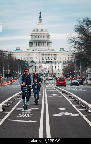 Eine Familie mit Elektrorollern nutzt die Fahrradwege auf den Straßen vor dem Kapitolgebäude der Vereinigten Staaten in Washington, D.C. Stockfoto