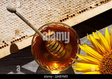 Frischer süßer Honig in einer Glasschüssel und Honigwaben auf einem alten Holztisch. Stockfoto