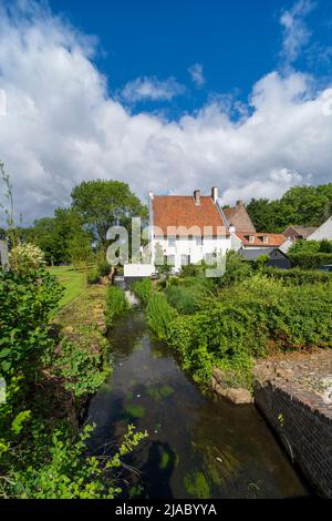 Ein weißes Gebäude neben einem Bach, umgeben von Grün in der Stadt Thorn, Niederlande Stockfoto