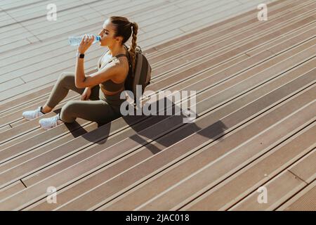 Die hübsche junge Frau macht eine Pause, nachdem sie im Stadtgebiet gelaufen ist Stockfoto