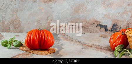 Rote Raf Coeur De Boeuf Tomaten und Basilikum auf braunem Hintergrund, Platz für Text, Restaurantkonzept, Stockfoto Stockfoto