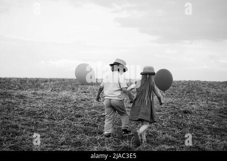 Konzept für die Kindheit. Unbeschwerte Kindheit. Frühling auf der Ranch. Schwester und Bruder arbeiten im Feld. Glückliches Kind auf dem Sommerfeld. Öko Resort Kind Stockfoto