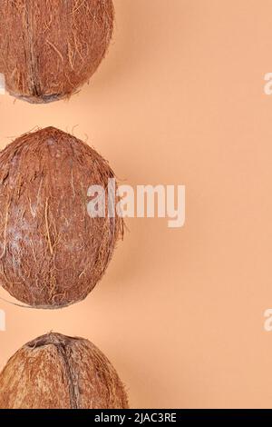 Draufsicht auf den Rand von braunen tropischen Kokosnüssen auf gelbem Hintergrund. Platz für Text. Stockfoto