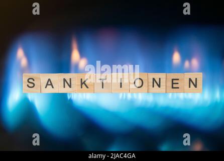 Holzwürfel mit der Aufschrift Sanktionen vor Einer großen Gasflamme Stockfoto