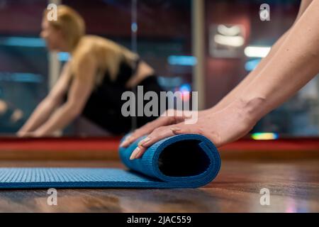 Frau Hände Rollen Yogamatte im Studio nach dem Üben Yoga-Training Stockfoto