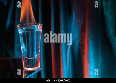 Glas mexikanischen Tequila, Wodka mit brennender Flüssigkeit. Glas Wodka auf Schwarz mit Flammen. Stockfoto