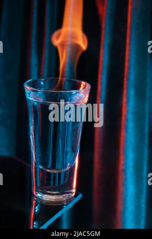 Glas mexikanischen Tequila, Wodka mit brennender Flüssigkeit. Glas Wodka auf Schwarz mit Flammen. Stockfoto