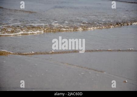 Sanfte Meereswelle am Sandstrand. Gezeiten am Strand. Bei Ebbe am Sandstrand am Meeresboden. Meer Sand Meer Strand Sommer Textur Stockfoto