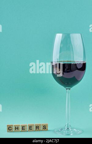 Ein Glas Rotwein und Holzklötze mit Aufschrift Jubel auf blauem Hintergrund. Platz für Text. Stockfoto