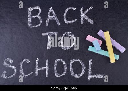 Handschriftliche Inschrift ZURÜCK IN DIE SCHULE auf schwarzer Tafel Nahaufnahme. Bildungskonzept. Stockfoto