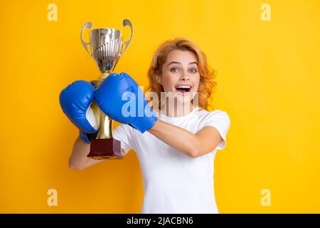 Fröhliche Frau, die den Sieg feiert. Frau in Boxhandschuhen hält Siegerpokal. Stockfoto