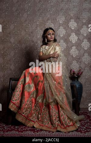 Indisches weibliches Model mit orangefarbenem und beigefarbenem Lehemga und Schmuck mit indischem Ethno-Look Stockfoto