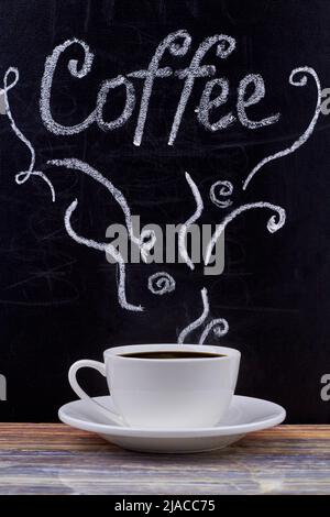 Handgeschriebene Beschriftung des Kaffees auf der Tafel und eine Tasse schwarzen Kaffee auf dem Holztisch. Kaffeepause-Konzept. Stockfoto