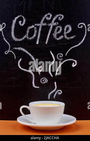 Handgeschriebene Beschriftung auf Tafel und Tasse Cappuccino auf Holztisch. Leckeres heißes Getränk. Stockfoto