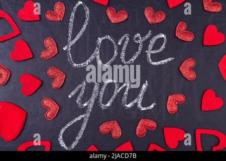 I love you Text geschrieben auf schwarzer Kreidetafel mit roten Herzen verziert. Handgeschriebene Liebesbotschaft. Stockfoto