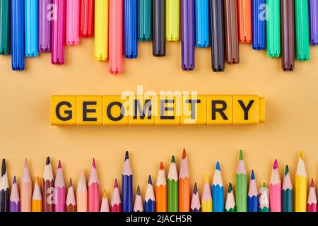 Das Wort GEOMETRIE auf Plastikwürfeln in Rahmen aus farbigen Schulmaterialien geschrieben. Schulbildungskonzept. Stockfoto