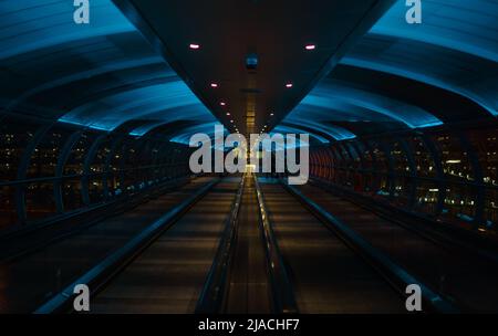 Skylink/Overhead-Travellator am Manchester International Airport, Greater Manchester, der einen neonähnlichen Effekt erzeugt. Stockfoto