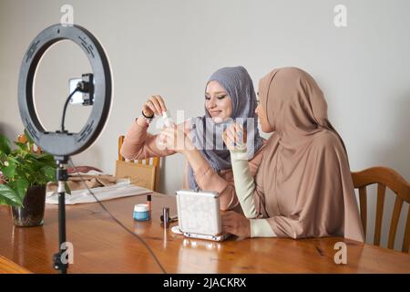 Influencer muslimische Frauen live Streaming Kosmetik Produktbewertung im Heimstudio. Stockfoto