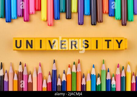 Satz Buntstifte und Universitätswort auf gelben Würfeln geschrieben. Flach liegend. Stockfoto