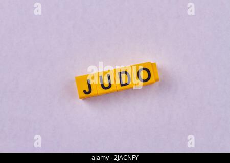 Das Wort Judo auf gelben Würfeln vor farbigem Hintergrund geschrieben. Art von Sport. Stockfoto