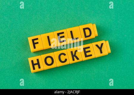 Die Aufschrift Hockey auf gelben Würfeln vor grünem Hintergrund. Sportart. Stockfoto