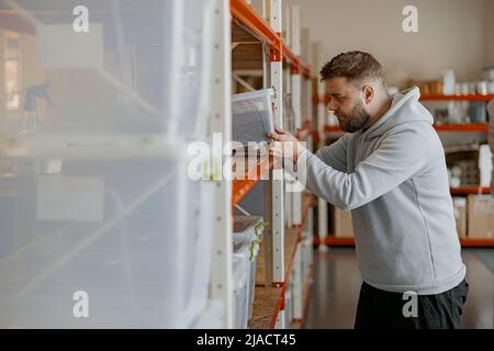 Unternehmer inspizieren Kisten mit gerösteten Kaffeebohnen auf einem Regal in einem Lager Stockfoto