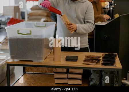 Nahaufnahme des Geschäftsinhabers verpackt geröstete Kaffeebohnen in Verpackungen zum Verkauf Stockfoto