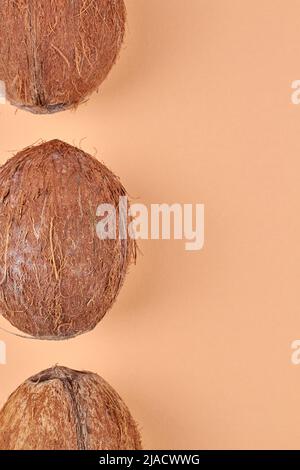 Draufsicht auf den Rand von braunen tropischen Kokosnüssen auf gelbem Hintergrund. Platz für Text. Stockfoto