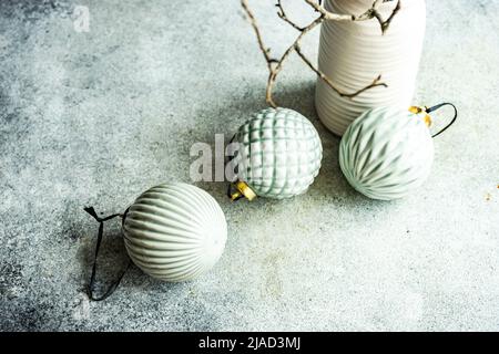 Blick von oben auf drei grüne Keramik-Weihnachtskugeln neben einer Vase Stockfoto