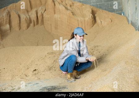 Bäuerin hockt auf einem Haufen Sojabohnenschalen Stockfoto