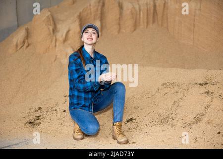 Bäuerin hockt auf einem Haufen Sojabohnenschalen Stockfoto