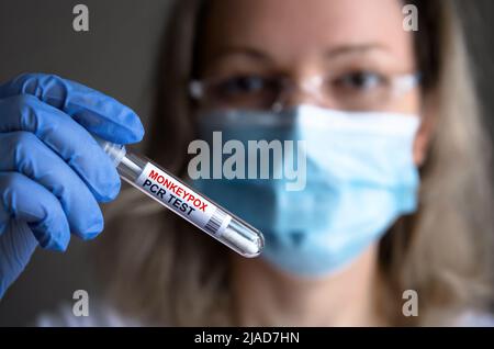 Monkeypox PCR-Teströhrchen in der Hand der Ärzte, medizinisches Personal in der medizinischen Maske zeigt Abstrichbesteck für Pockenvirus-Diagnose und Affenpocken-Forschung Stockfoto