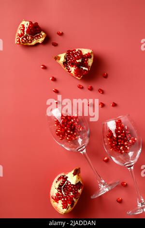Gläser mit Granatapfel auf rotem Hintergrund. Granatapfel-Weinkonzept. Flach liegend, Draufsicht. Stockfoto