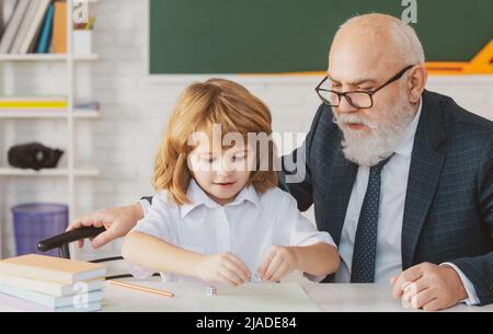 Oberlehrer oder Großvater und Schüler im Klassenzimmer der Schule. Privatunterricht. Alte Tutor Lehrer helfen kleinen Jungen Schüler mit dem Studium der Mathematik Stockfoto