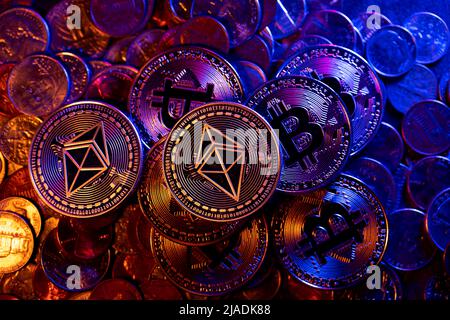 Ethereum und Bitcoin auf Haufen von Euro- und Dollar-Münzen. Handel mit volatiler Kryptowährung Stockfoto