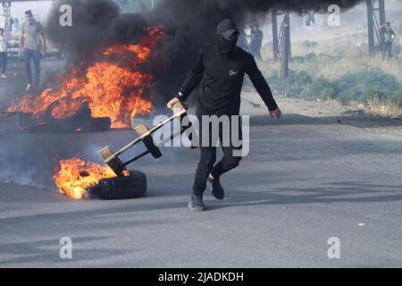 Nablus, Westjordanland, Palästina. 27.. Mai 2022. Palästinensische Demonstranten verbrennen Reifen während einer Demonstration gegen das Eindringen jüdischer Siedler in die Al-Aqsa Moschee und die Organisation des marsches israelischer Flaggen in ihren Mauern, in der Nähe des israelischen Kontrollpunkts Hawara südlich der Stadt Nablus im besetzten Westjordanland. (Bild: © Nasser Ishtayeh/SOPA Images via ZUMA Press Wire) Stockfoto