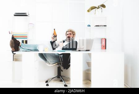 Müde gelangweilte Geschäftsmann Gähnen am Arbeitsplatz in der Nähe von Laptop, langweilige Arbeit, Sackgasse Job, Überarbeit extra nach Stunden, Alkohol trinken. Stockfoto