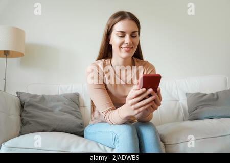 Junge Millennial Teenager Frau mit Smartphone auf dem Sofa sitzen Ansicht von unten Stockfoto