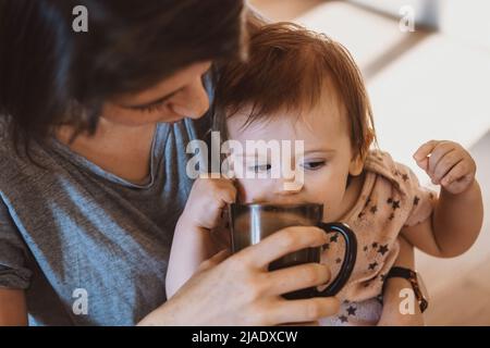 Nahaufnahme eines Porträts von junger Mutter und Tochter, die in der Küche gesund frühstücken. Schöne junge Frau. Babypflege. Familienbetreuung. Stockfoto